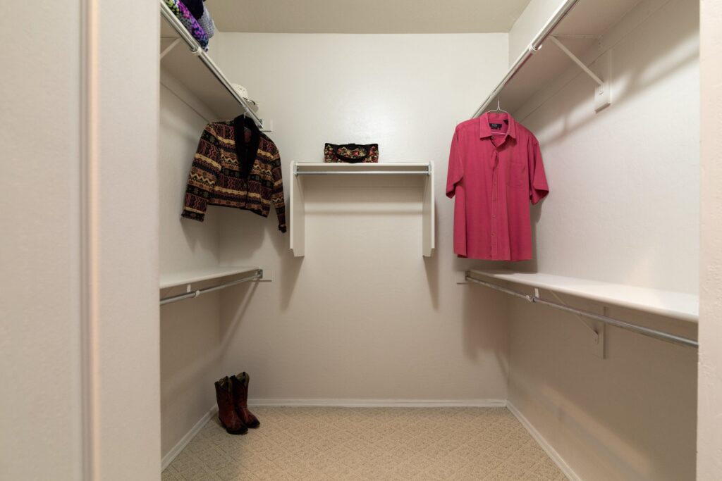 Walk in closet with a few things hanging in it